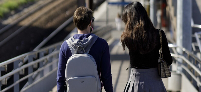 Photo de deux voyageurs de dos capturée en gare de Stade de France - Saint-Denis. L'un porte un sac à dos, pour illustrer le thème des affaires oubliées en gare.